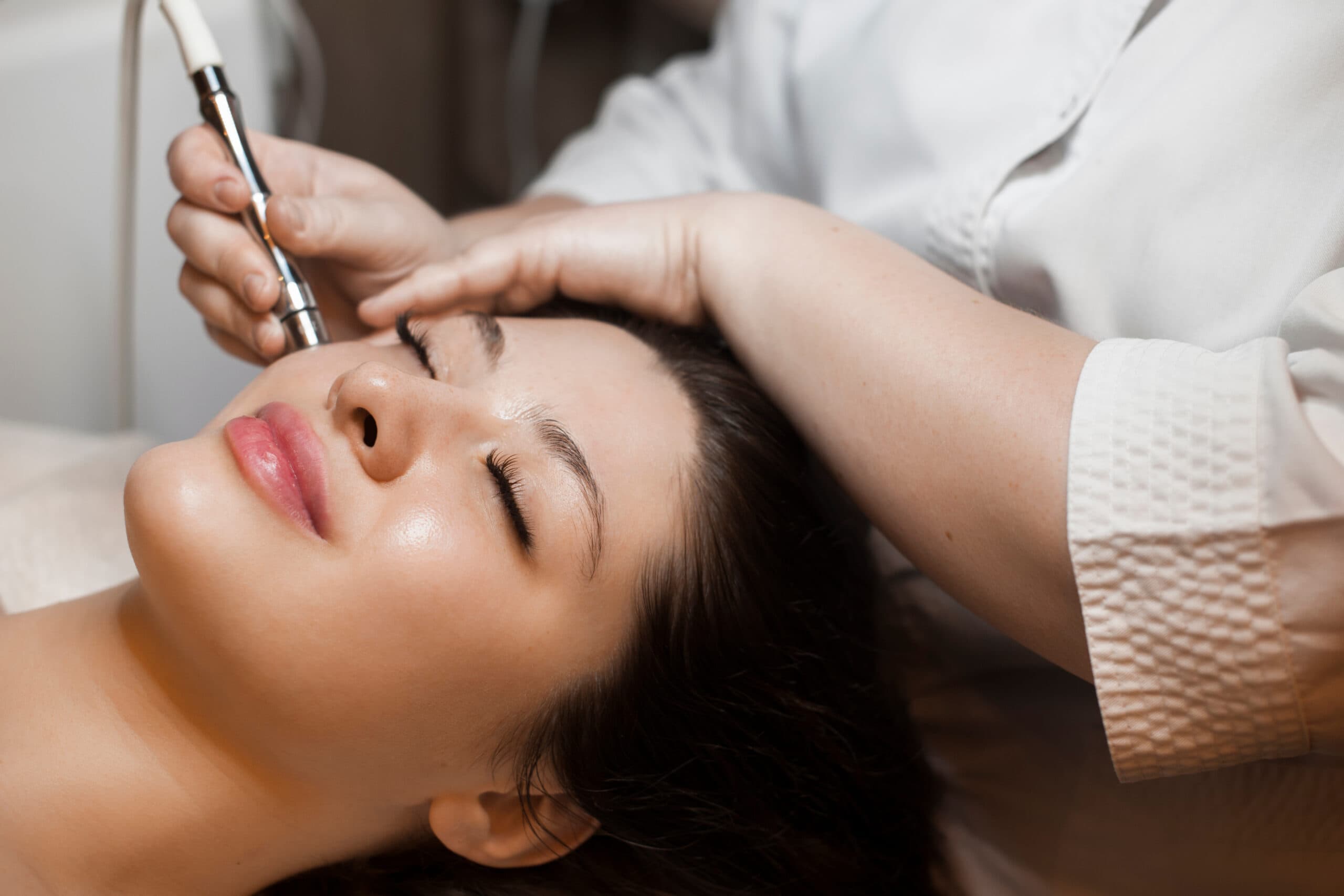 Woman at a beauty salon getting a professional microneedling service done by a certified beauty technician.