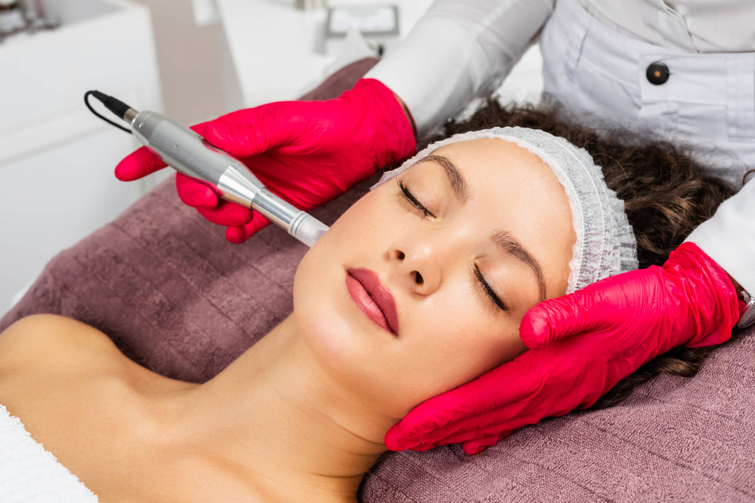 A woman getting microneedling done on her face by a beauty technician in Jacksonville, FL.